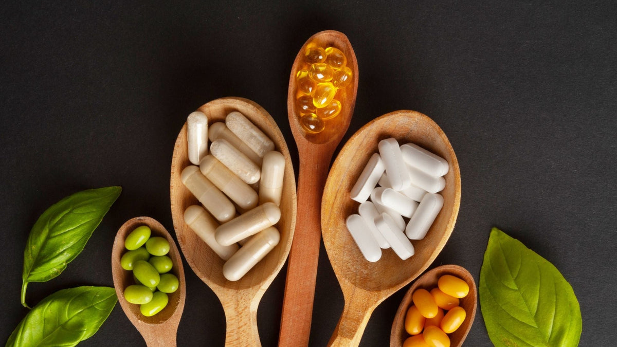 Cápsulas y suplementos nutricionales variados sobre cucharas de madera, representando el uso de vitaminas y minerales para prevenir deficiencias.