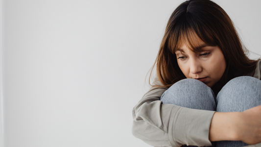 Mujer con la mirada baja, abrazando sus rodillas, una imagen asociada al malestar emocional