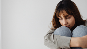 Mujer con la mirada baja, abrazando sus rodillas, una imagen asociada al malestar emocional