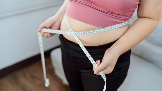 Mujer midiendo su circunferencia de cintura con una cinta métrica