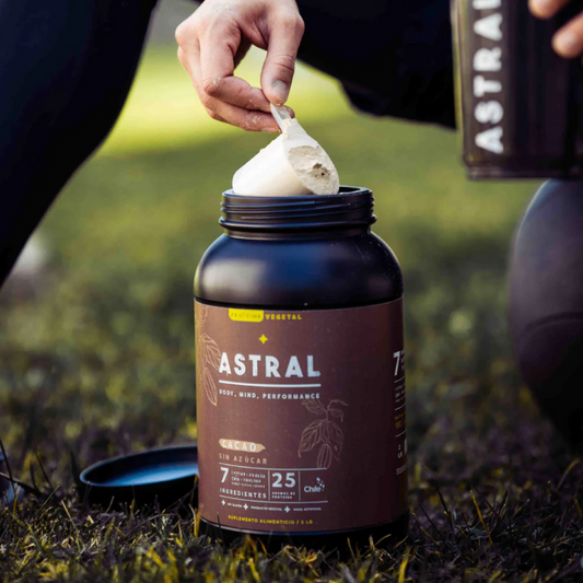 Frasco de Proteína Lupino Cacao Astral con cuchara de plástico en ambiente natural, 910 gramos, Ortomolecular Chile 